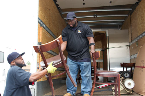 Two Workers Loading Chairs Off Truck