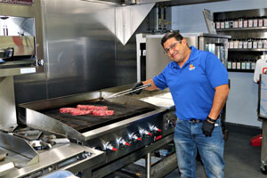 ACityDiscount employee grill steaks on a range.