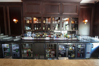 A well-organized and stocked bar with Krowne refrigeration and back bar equipment